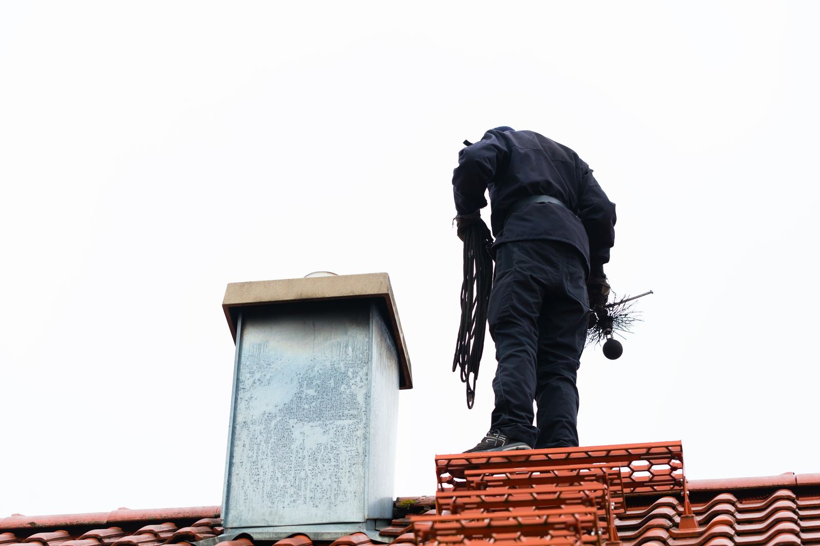 A sweep works a flue from the roofline